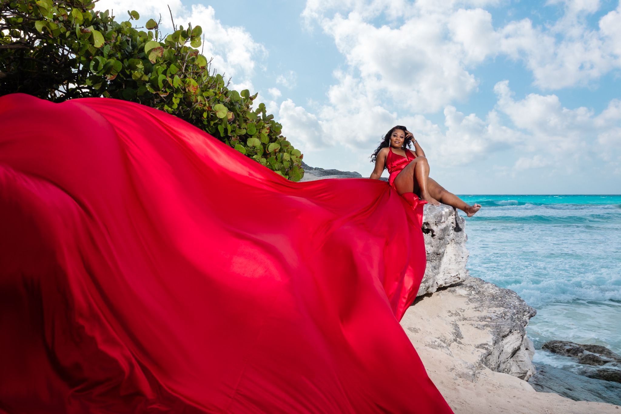 Tonya M. Holmes in a red dress beside the turquoise ocean