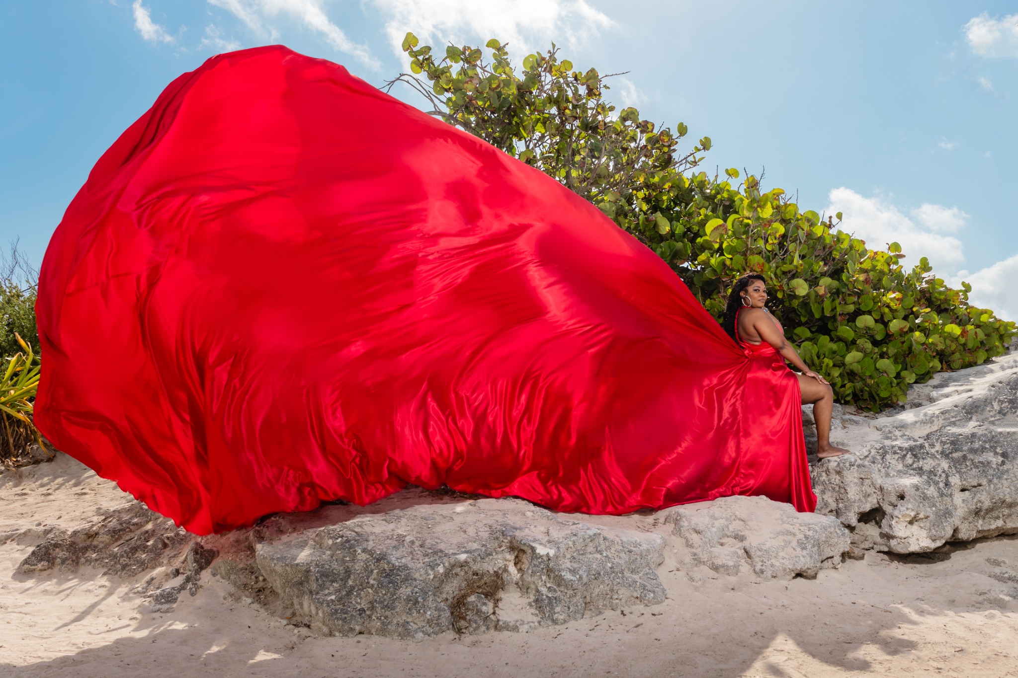 Tonya M. Holmes posing in a flowing red dress at the beach